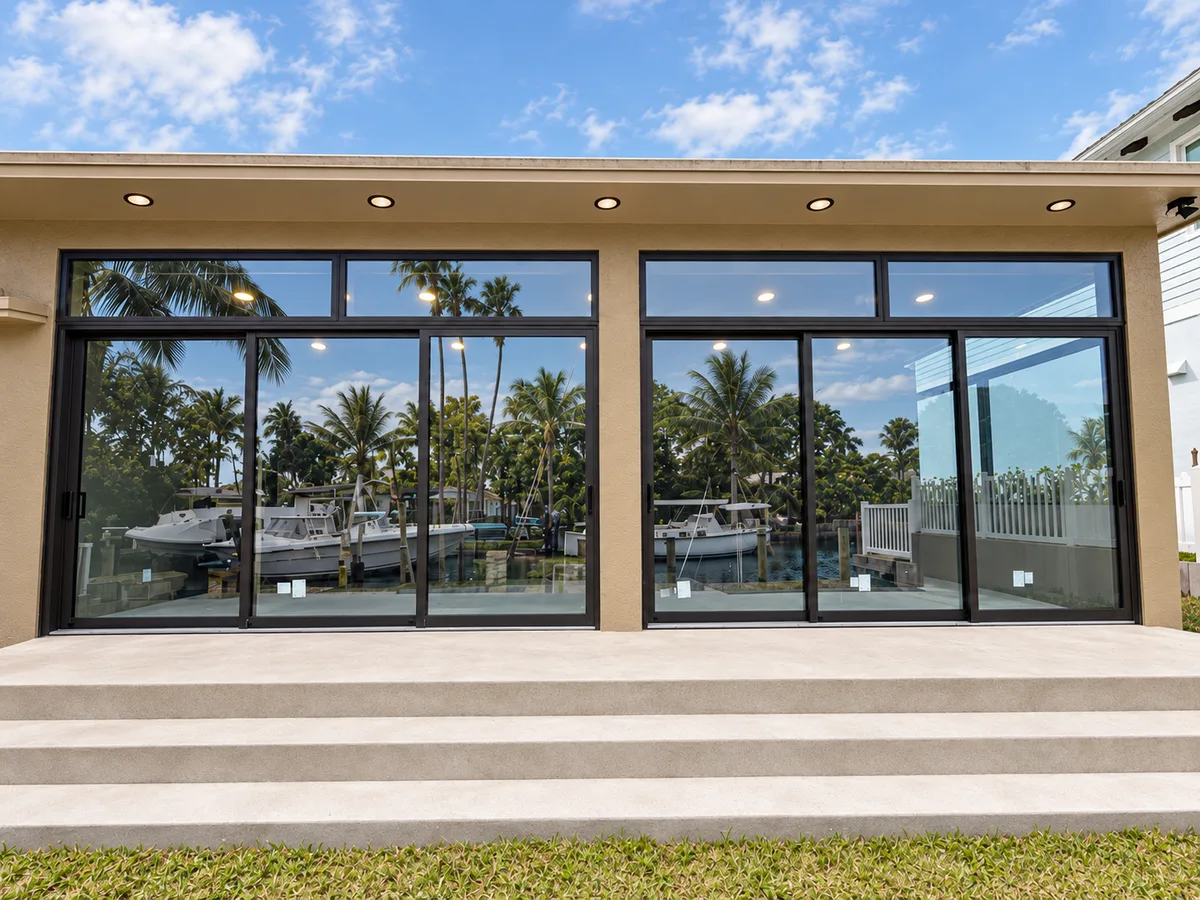 Floor-to-ceiling multi-panel impact sliding glass doors overlooking a luxury South Florida waterfront estate pool and dock