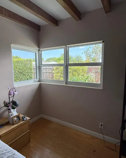 White casement impact windows wrapping the corner of a bedroom with a view of the garden