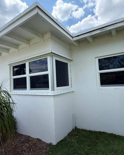 White casement impact windows on the corner bay of a white single-story house