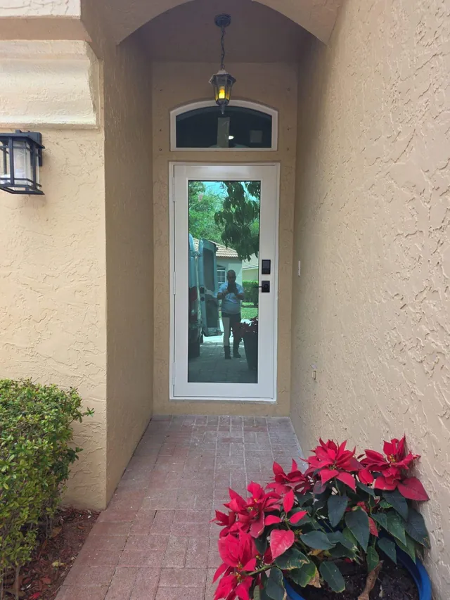 White-frame single impact French door with an arched eyebrow transom window at the end of a garden walkway