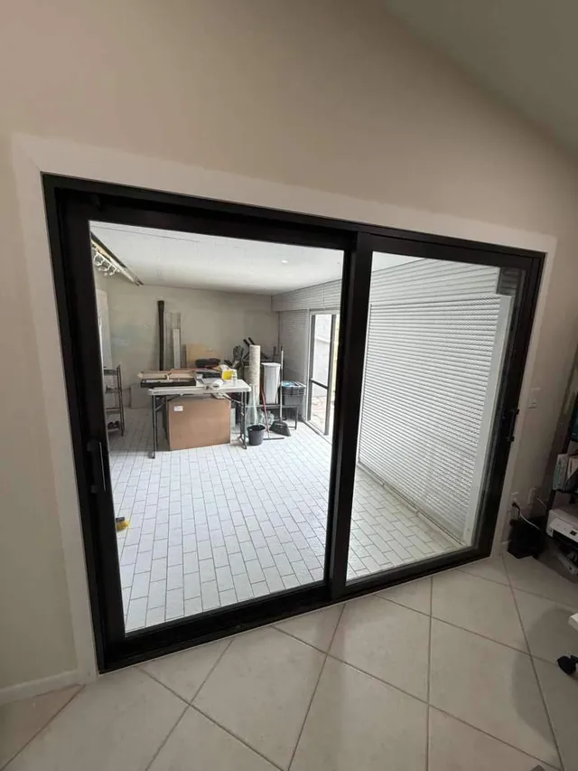 Dark bronze two-panel impact sliding glass door installed in a residential patio opening