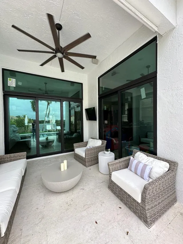 Two dark bronze impact sliding glass doors with transom windows on a covered patio with outdoor seating