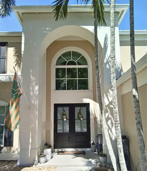 Dark double impact entry doors with glass panels under a tall arched transom window