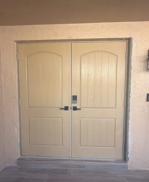 Tan double impact fiberglass doors with arched plank panels and a keypad deadbolt
