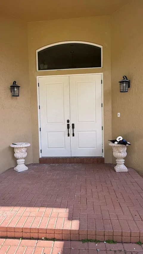 White double impact fiberglass doors with an arched transom above, on a brick paver porch