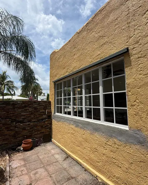 Long row of white fixed impact windows with grids in a yellow stucco wall
