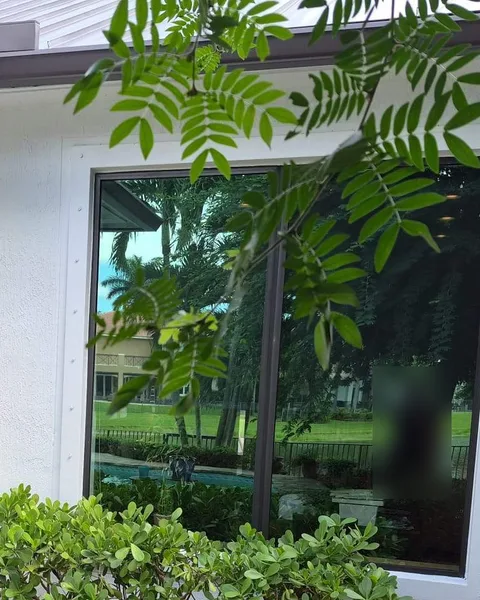 Large white-frame fixed impact window beside an impact sliding glass door on a covered patio facing a pool