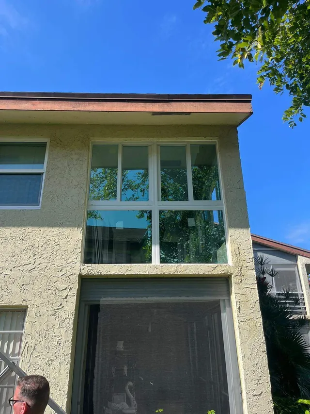 Exterior view of a second-story balcony Florida room enclosure with white-frame fixed lower panes and horizontal roller upper windows