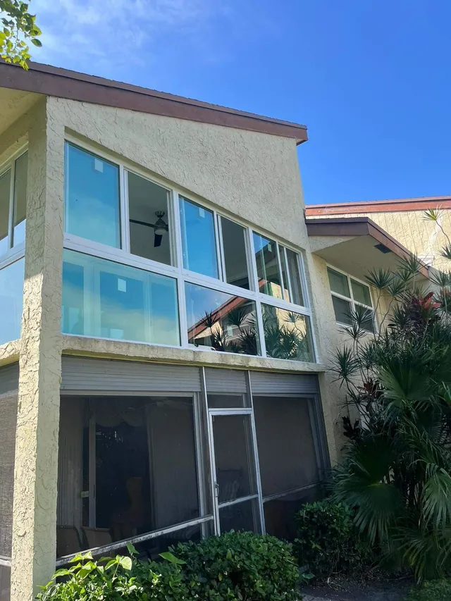 Angled exterior view of a second-story white-frame Florida room enclosure integrated into a stucco facade
