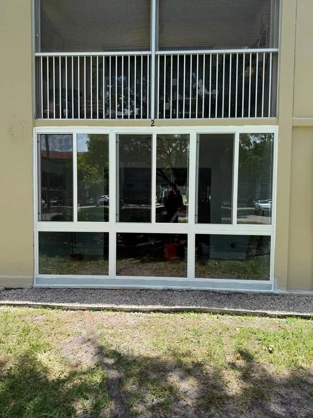 Angled exterior view of a ground-floor Florida room enclosure with white-frame horizontal roller and fixed impact windows