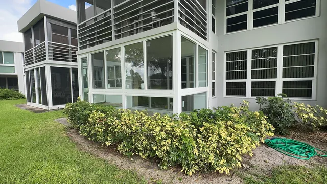 Exterior view of a white-frame Florida room enclosure spanning the ground floor of a South Florida residential building