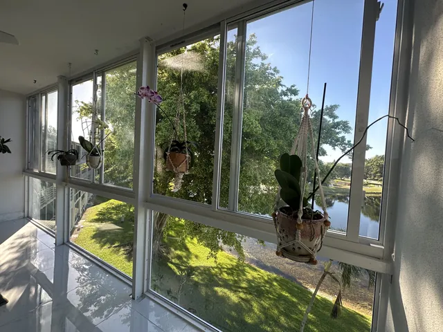 Sunlit interior of a lakefront Florida room enclosure with glossy white floor tile and floor-to-ceiling white-frame impact glass