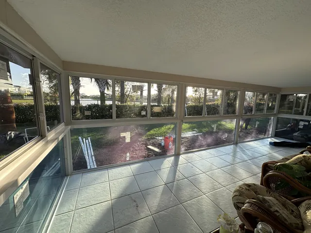 Corner interior view of a white-frame Florida room enclosure showing structural vertical mullion posts and full-height impact glazing