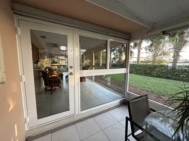 Interior transition showing white-frame impact French doors opening into a newly enclosed glass Florida room