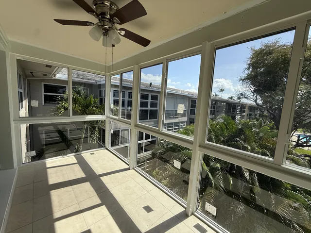 Bright second-story Florida room interior with ceiling fan, tiled floor, and white-frame horizontal roller impact windows