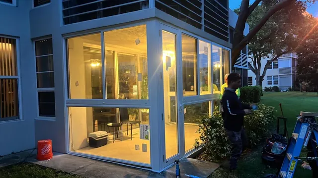 Dusk exterior view of a lit Florida room enclosure showcasing clear floor-to-ceiling white-frame impact glass panels