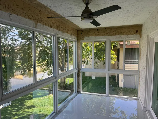 Interior framing stage of a Florida room conversion showing newly set white-frame horizontal roller impact windows