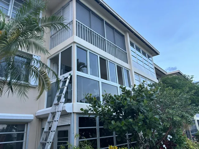 Exterior view of a two-story home with a second-floor white-frame impact glass Florida room enclosure
