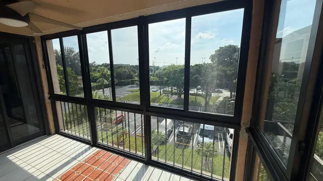 Wide interior view of a balcony Florida room enclosed with bronze-frame fixed lower panes and horizontal roller upper impact windows
