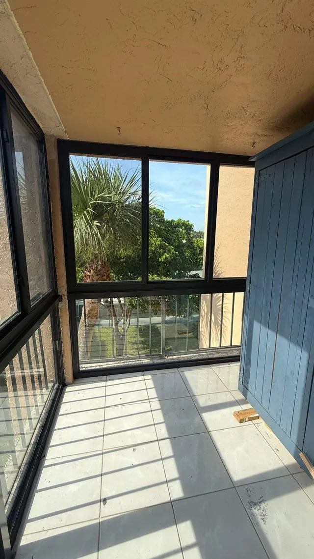 Vertical interior detail of a bronze-frame Florida room corner mullion post and floor-to-ceiling impact glass assembly