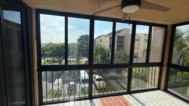 Straight-on interior view of a four-bay bronze-frame Florida room enclosure with operable horizontal roller windows and fixed lower glass