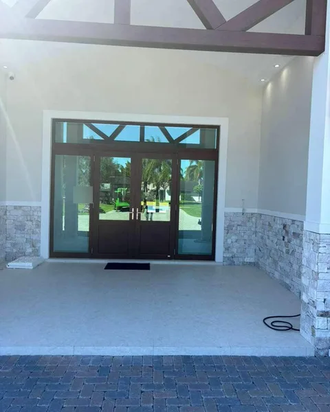 Bronze double impact entry door with glass sidelites and a transom under a covered porch