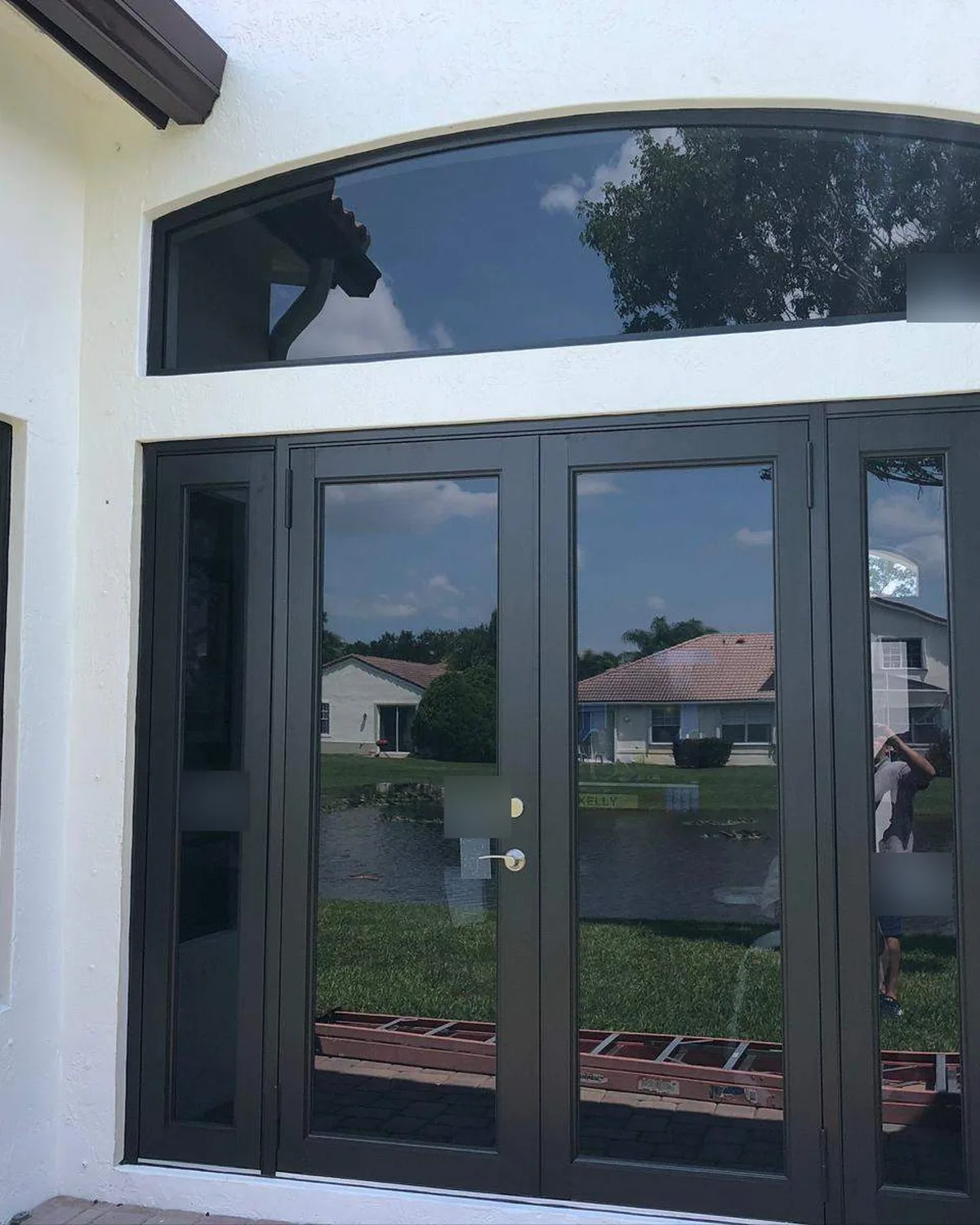 Monumental bronze impact French entry doors with sidelites and arched transom installed in Fort Lauderdale