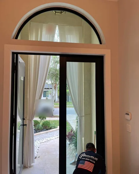 Republic installer fitting a black-frame impact glass entry door under an arched transom window