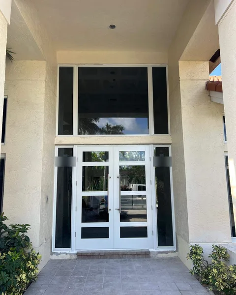 White double impact entry door with tall sidelights and a large transom window under a covered entry