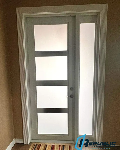 Inside view of a white single impact entry door with four frosted glass panels and a frosted sidelite