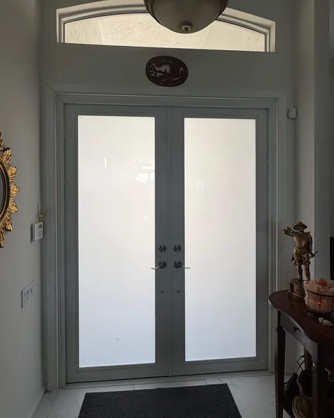 White double French impact doors with frosted glass under a transom window, seen from the foyer of a house in Palm Beach County