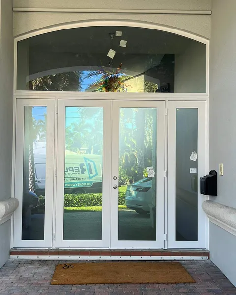 White-frame double French impact entry doors with sidelites under an arched transom