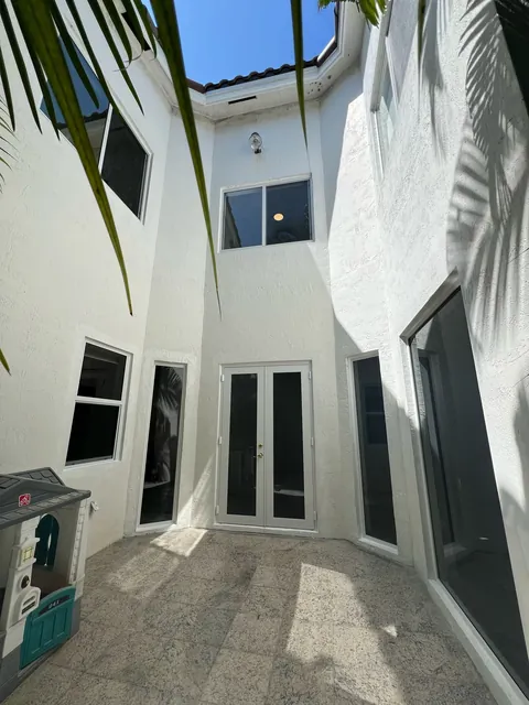 White courtyard with white-frame impact French doors and matching impact windows