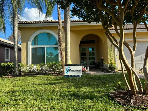 Yellow home with a white arched impact window, glass impact front doors and a Republic yard sign