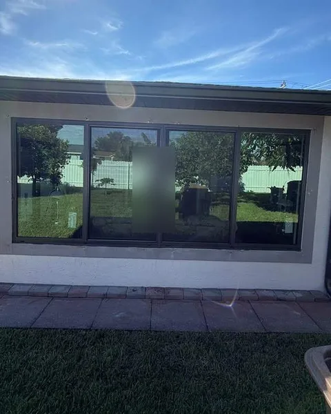 Bronze-frame four-lite fixed picture impact window on the back wall of a house