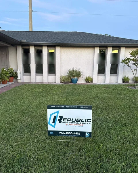 Bronze-frame single-hung impact windows between white columns with a Republic yard sign on the lawn