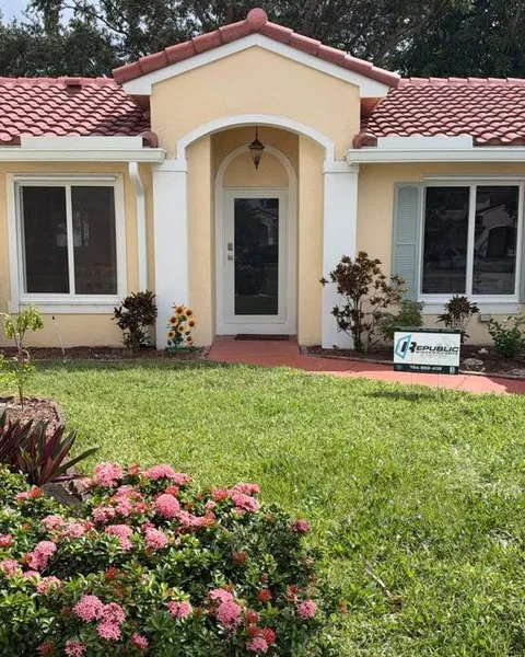 Single-family home with new white single-hung impact windows, a white impact front door, and a Republic yard sign