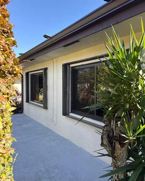 Bronze-frame horizontal roller impact windows along the side of a white house in Greenacres