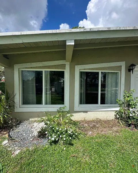 Two white-frame horizontal roller impact windows on a single-story house with a garden in front