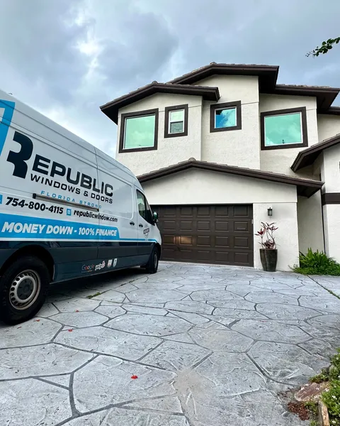 Republic service van parked in front of a two-story home with new dark-frame impact windows