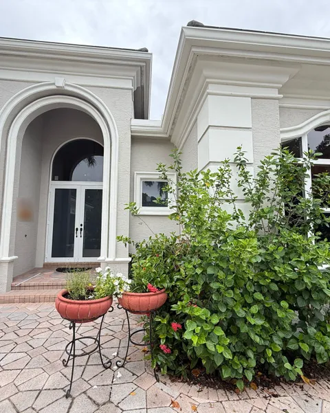 White impact French doors under an arched entry, next to a tall arched impact window