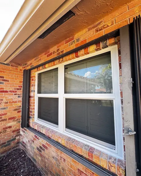 Pair of white single-hung impact windows set in a brick wall