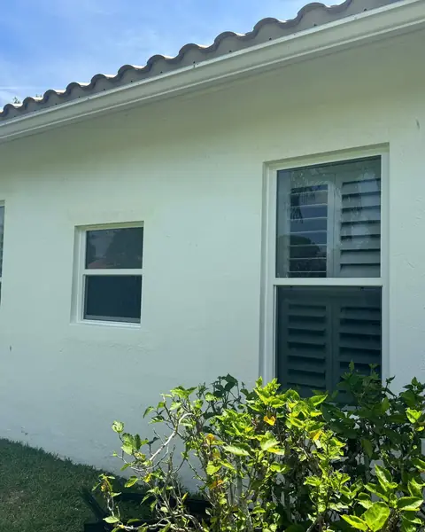 Three white single-hung impact windows along the side of a white house in Palm Beach County