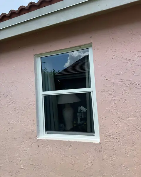 White single-hung impact window in a pink stucco wall in Pembroke Pines