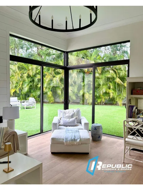 Interior view of bronze-frame impact sliding glass doors meeting at a corner, with transoms above