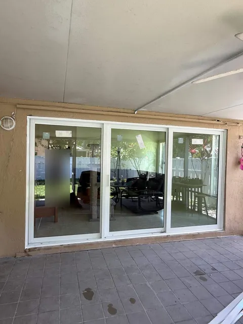 White three-panel impact sliding glass door on a covered patio