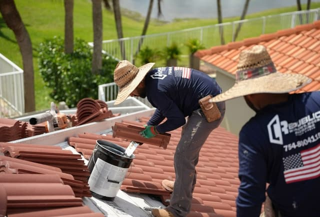 Roofing crew laying barrel tile on a South Florida home